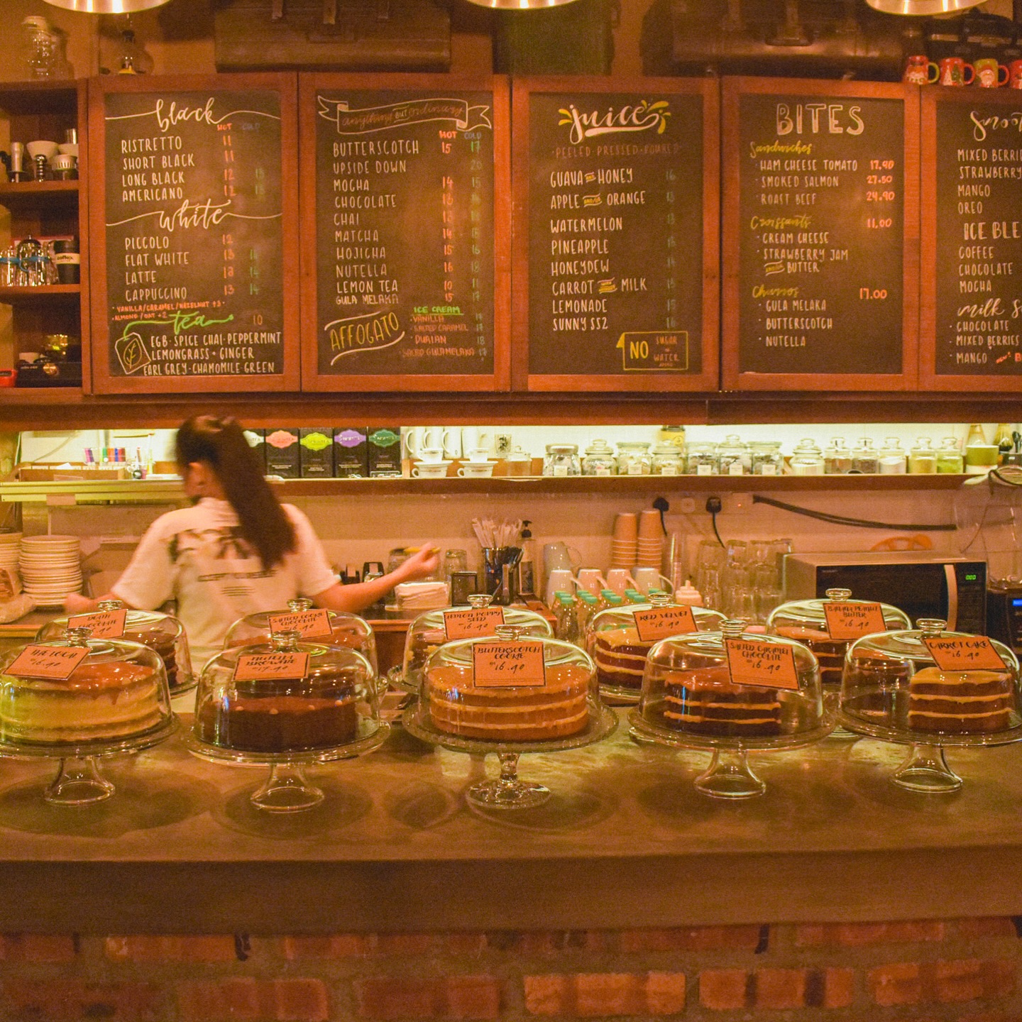 The Rekindle counter — hand-chalked menu boards above a row of whole cakes under glass domes