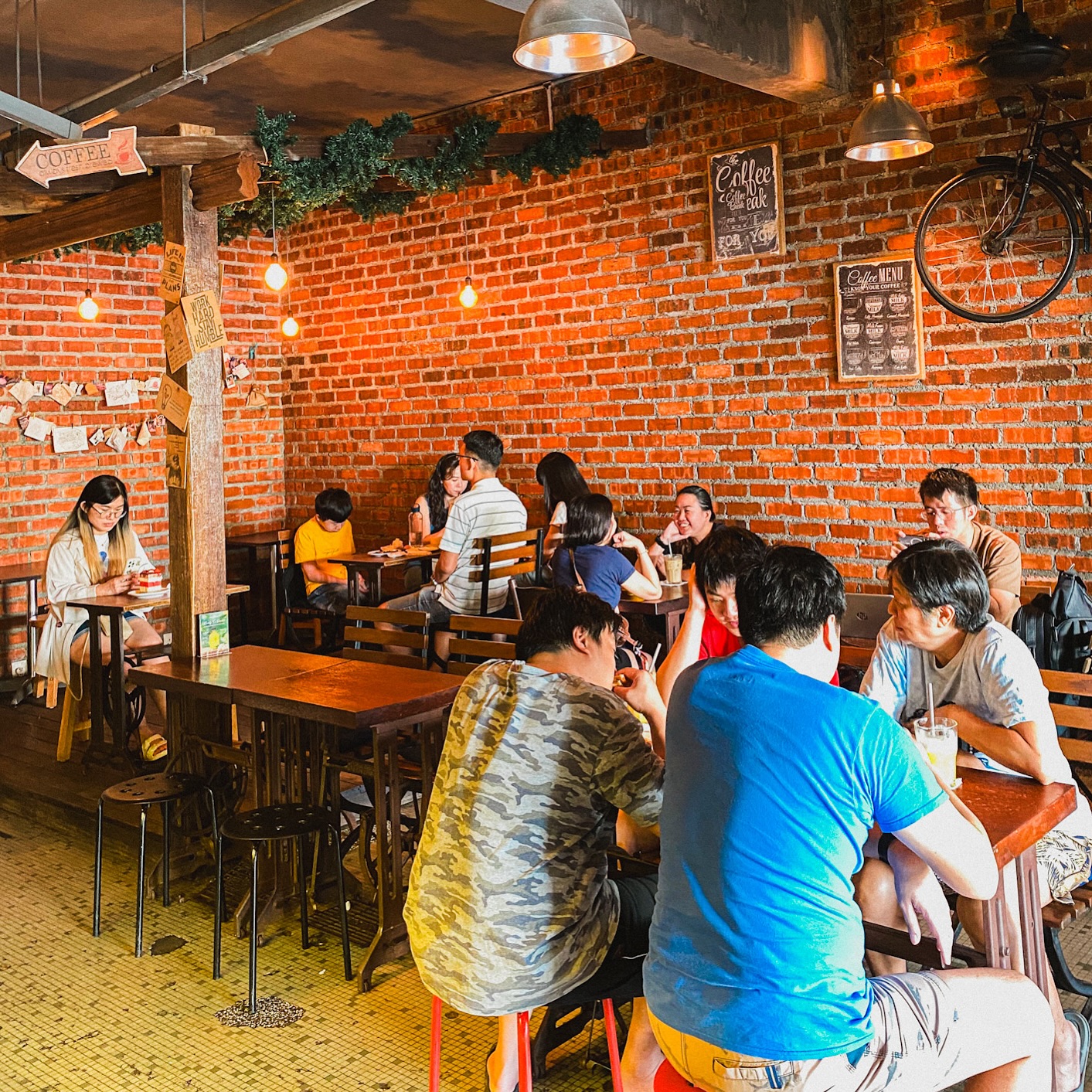 Inside Rekindle — a warm, brick-walled room of reclaimed-timber tables with regulars settled in over coffee